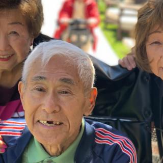 A group of elderly people smiling and enjoying time outdoors.