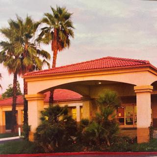 A charming building surrounded by palm trees at sunset.