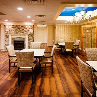 A cozy dining room with a fireplace, elegant furniture, and wooden flooring.