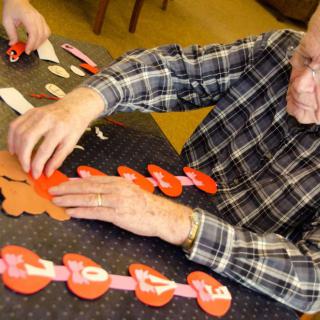 An elderly person engaged in a crafting activity, arranging paper heart decorations.