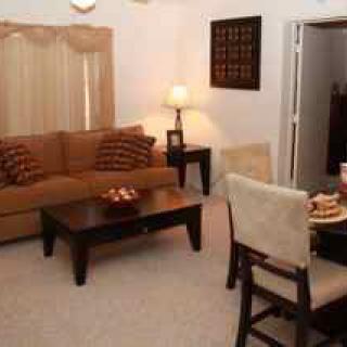 A cozy living room with a sofa, coffee table, and dining area.
