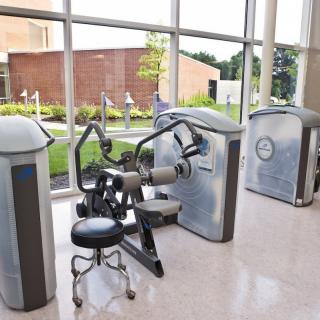 A modern gym setup with various exercise machines by large windows.