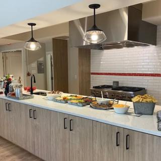 A modern kitchen with a counter set up with food and pendant lighting.