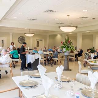 An elegant indoor dining area with patrons seated at tables, served by attentive waitstaff.