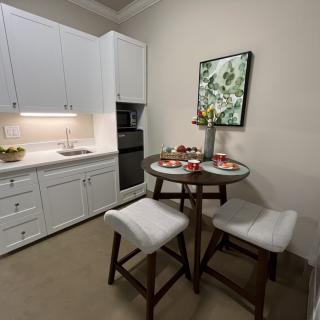 A cozy kitchen with a modern dining area featuring a round table and cushioned stools.