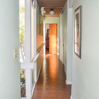 A bright hallway with wooden flooring and a door at the end.