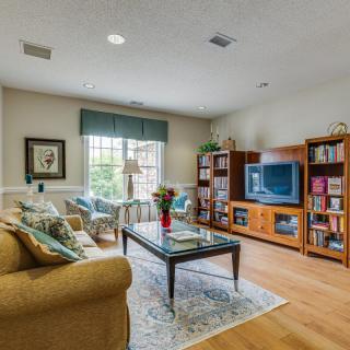 Cozy living room with a sofa, coffee table, and bookshelves, featuring a television and a large window.