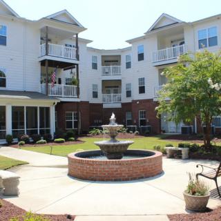A view of a residential apartment courtyard with a central fountain and surrounding greenery.