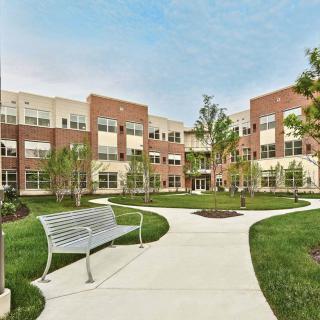 A modern brick building with a landscaped courtyard and winding pathways.