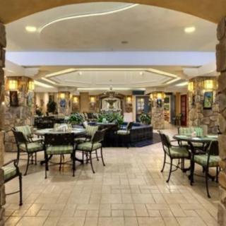 A spacious lobby area with stone walls, elegant tables and chairs, and indoor plants.