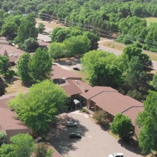 Aerial view of a residential area with several buildings surrounded by trees and parking spaces.