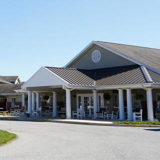 A large building with a porch and columns, featuring a gabled roof, captured on a clear day.