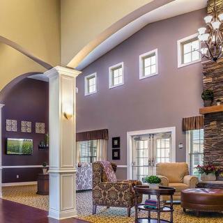 A cozy and elegant living room with high ceilings, featuring comfortable seating and a fireplace.