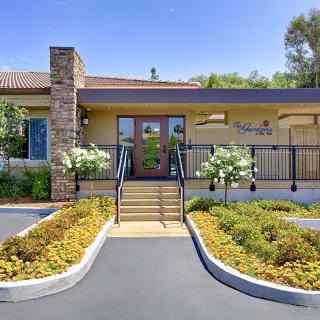 A modern building entrance with well-maintained landscaping and a clear blue sky.