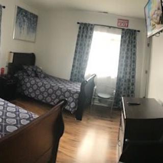 A cozy bedroom with two beds, patterned curtains, and a wall-mounted TV.
