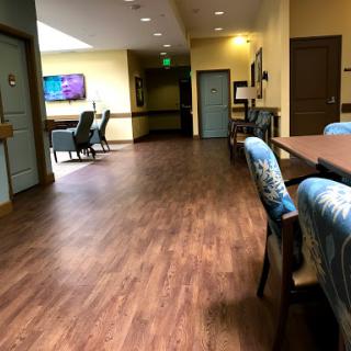 A well-lit hallway featuring a spacious layout with chairs and a table, ideal for gatherings or meetings.
