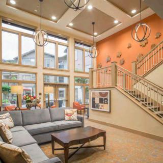 A modern and spacious living room with a large sofa, stylish lighting fixtures, and a staircase in the background.