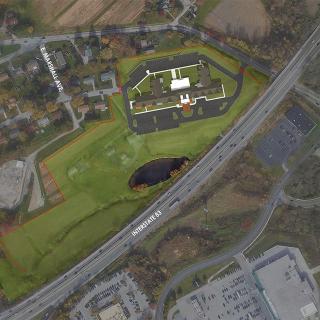 Aerial view of a large building complex surrounded by roads and greenery.