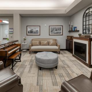 A cozy living room featuring a sofa, piano, and fireplace with modern decor.