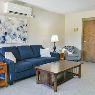 A cozy living room with a blue sofa, wooden coffee table, and wall-mounted artwork.