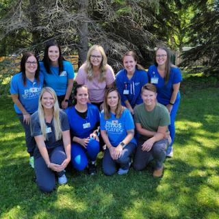 A cheerful team of healthcare professionals gathered together in a sunny outdoor setting.