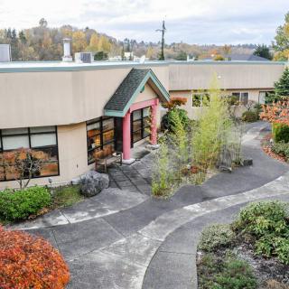 A scenic view of a building surrounded by an autumnal garden with winding pathways.