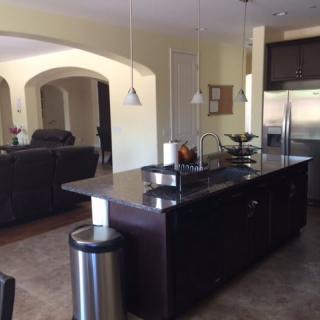 A modern kitchen with an island countertop and a view into the living room.