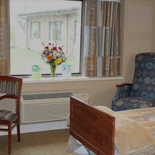 A cozy room with a bed, chair, and window adorned with flowers.