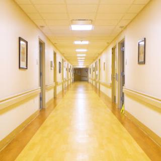 A serene hospital hallway with well-lit surroundings and framed artwork on the walls.