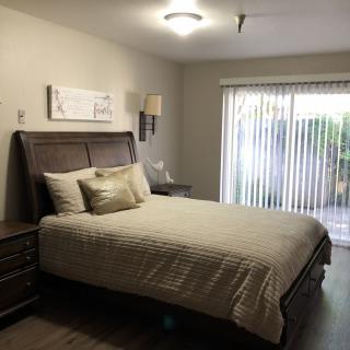 A neatly arranged bedroom with a bed, nightstands, and a large window with curtains.