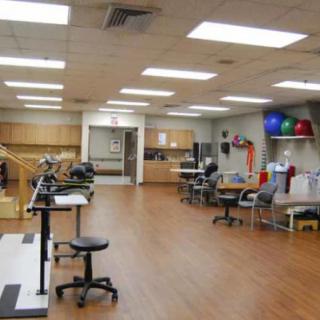 A spacious rehabilitation room equipped with various physical therapy equipment and exercise tools.
