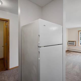 A glimpse into a modern kitchen featuring a white refrigerator and an open living area.