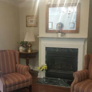 A cozy living room featuring striped chairs and a decorative fireplace.