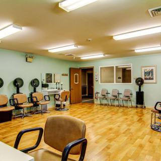 An interior view of a salon with multiple chairs and hair dryers lined against the wall.