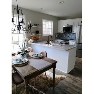 A modern kitchen and dining area with a wooden table, chairs, and a chandelier.