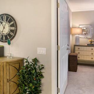 A cozy living space featuring a wall clock, cabinet, and stylish lighting.
