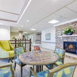 A cozy living room with a round table, colorful chairs, and a fireplace.