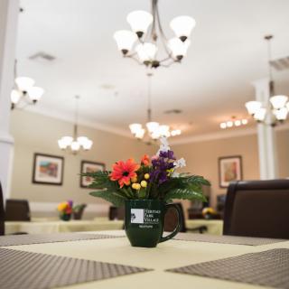 A cozy dining room with elegant chandeliers and a floral centerpiece on the table.