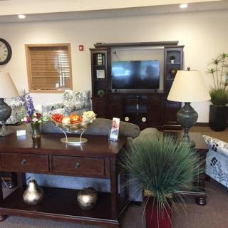 A cozy living room setup featuring a television, sofas, a wooden table with lamps, and decorative plants.