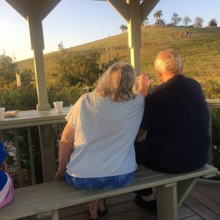 A couple enjoys the sunset together under a gazebo.
