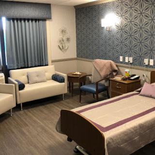A well-lit and thoughtfully designed hospital patient room featuring a bed, seating area, and modern decor.