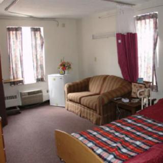 A cozy room with a bed, sofa, and windows covered with curtains.