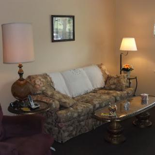 A cozy living room setup featuring a floral sofa, elegant lamps, and a glass coffee table.
