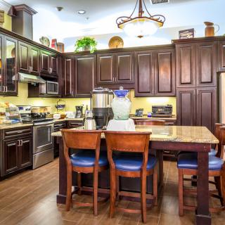A modern kitchen with wooden cabinets, a central island, and bar stools.