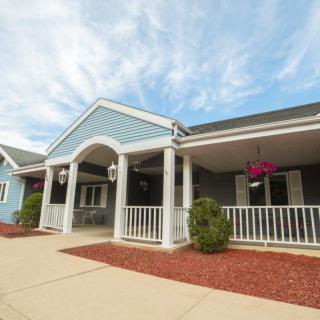 A charming house with a front porch and well-maintained landscaping under a blue sky.