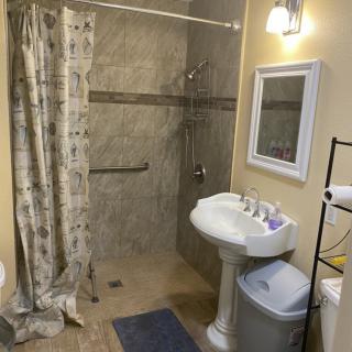 A clean and organized bathroom with a shower, sink, and mirror under a light.