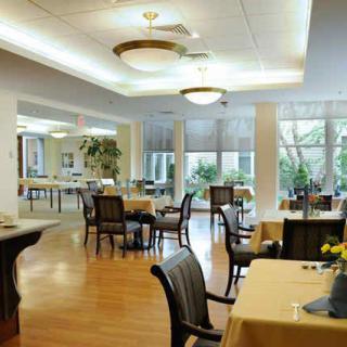 A spacious dining room with tables and chairs, featuring large windows and elegant lighting.