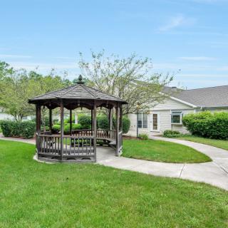 A scenic garden with a gazebo and winding pathway leading to a building.