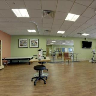 A spacious physical therapy room with various exercise equipment and treatment areas.