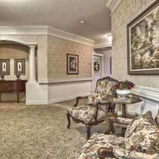 A traditional-style interior hallway with ornate chairs and artwork on the walls.